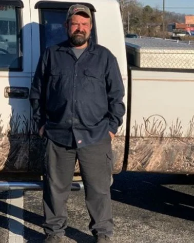 Brian Robertson, owner of Clean Cut Lawn Care, standing beside his pickup truck